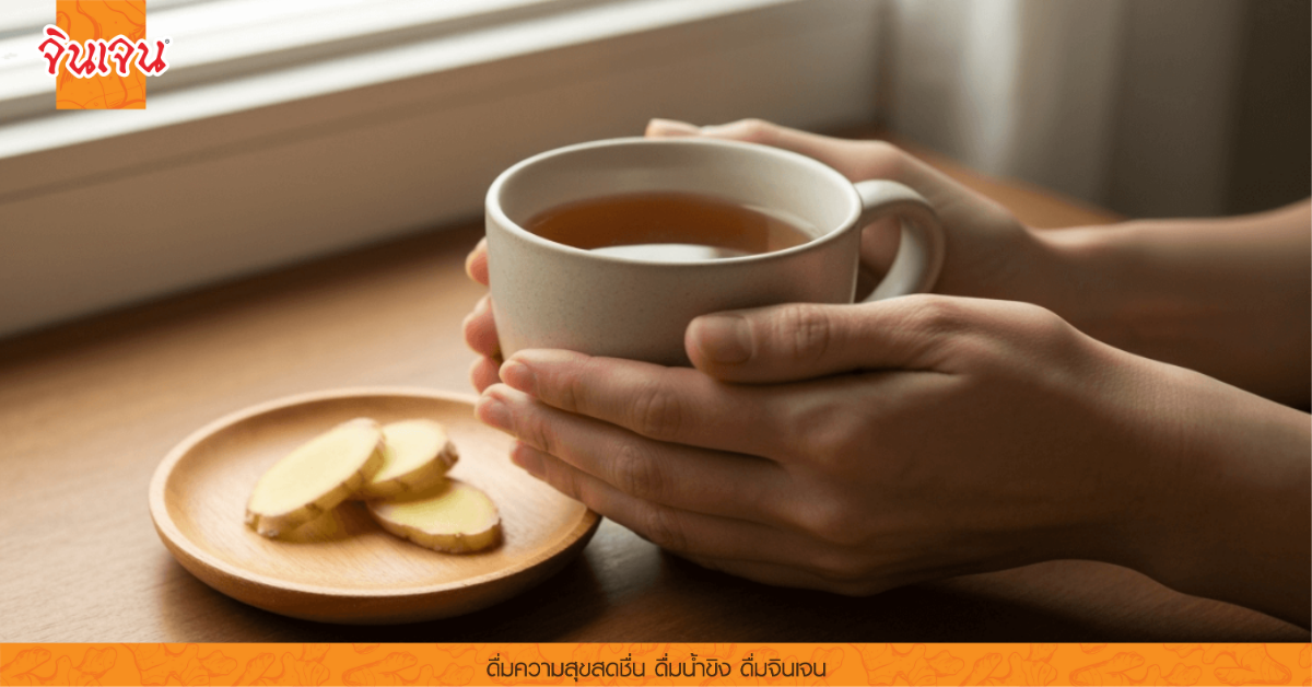 มือกำถ้วยชาผสมขิงบนโต๊ะไม้